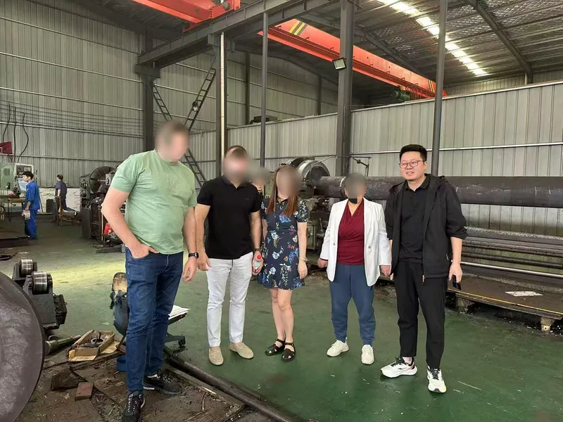 Приехавшие клиенты и сотрудники Linyao стоят в ряд под цеховым краном.